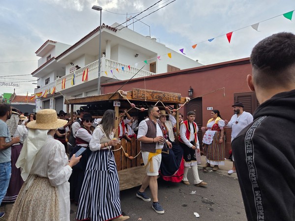 Romería de Tejina, Tenerife Grupo de personas con trajes típicos en la romería de Tejina, Tenerife, desfilando junto a una carreta decorada en una calle festiva.