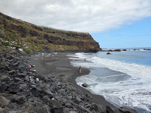 Playa El Bollullo Playa El Bollullo con su característica arena negra volcánica y visitantes disfrutando del paisaje natural.