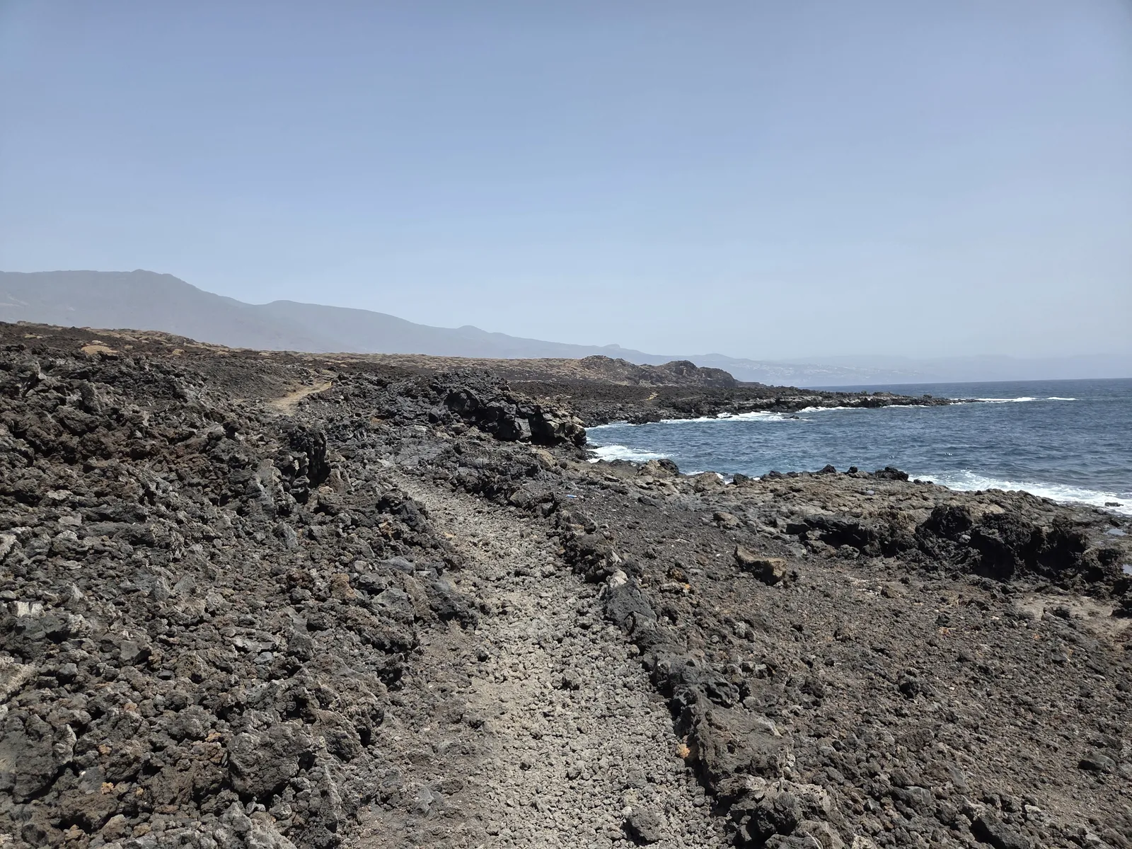 Caminata por el paisaje volcánico costero del Malpaís de Güímar Camino entre coladas volcánicas junto al mar en el Malpaís de Güímar, Tenerife
