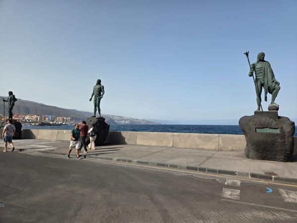 Estatuas de los menceyes en Candelaria Estatuas de los menceyes guanches frente al mar en Candelaria, con personas caminando cerca.