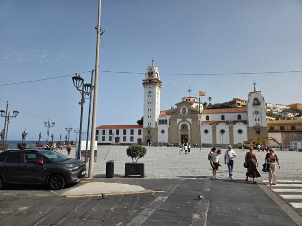 Vista frontal de la Basílica de Candelaria con visitantes en la plaza y estatuas guanches al fondo.