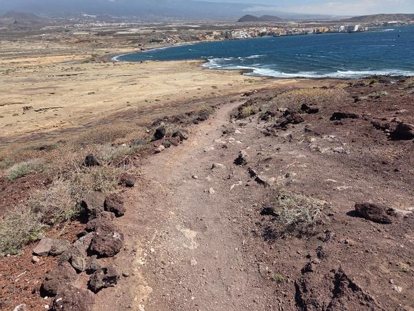 Camino hacia la costa en El Médano Sendero de tierra con vista panorámica hacia la costa de El Médano y el océano Atlántico.