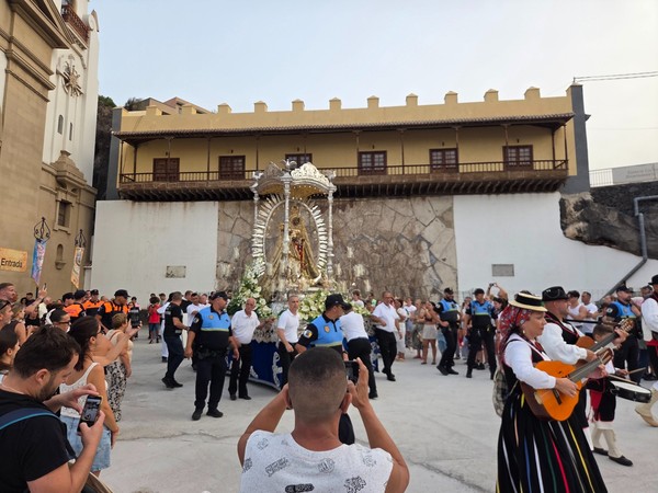 Procesión festiva en Candelaria con una imagen religiosa, músicos tradicionales y público reunido en la plaza.