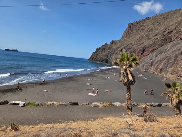 Playa de Las Gaviotas Playa de Las Gaviotas en Tenerife con arena oscura, bañistas y montañas volcánicas al fondo.