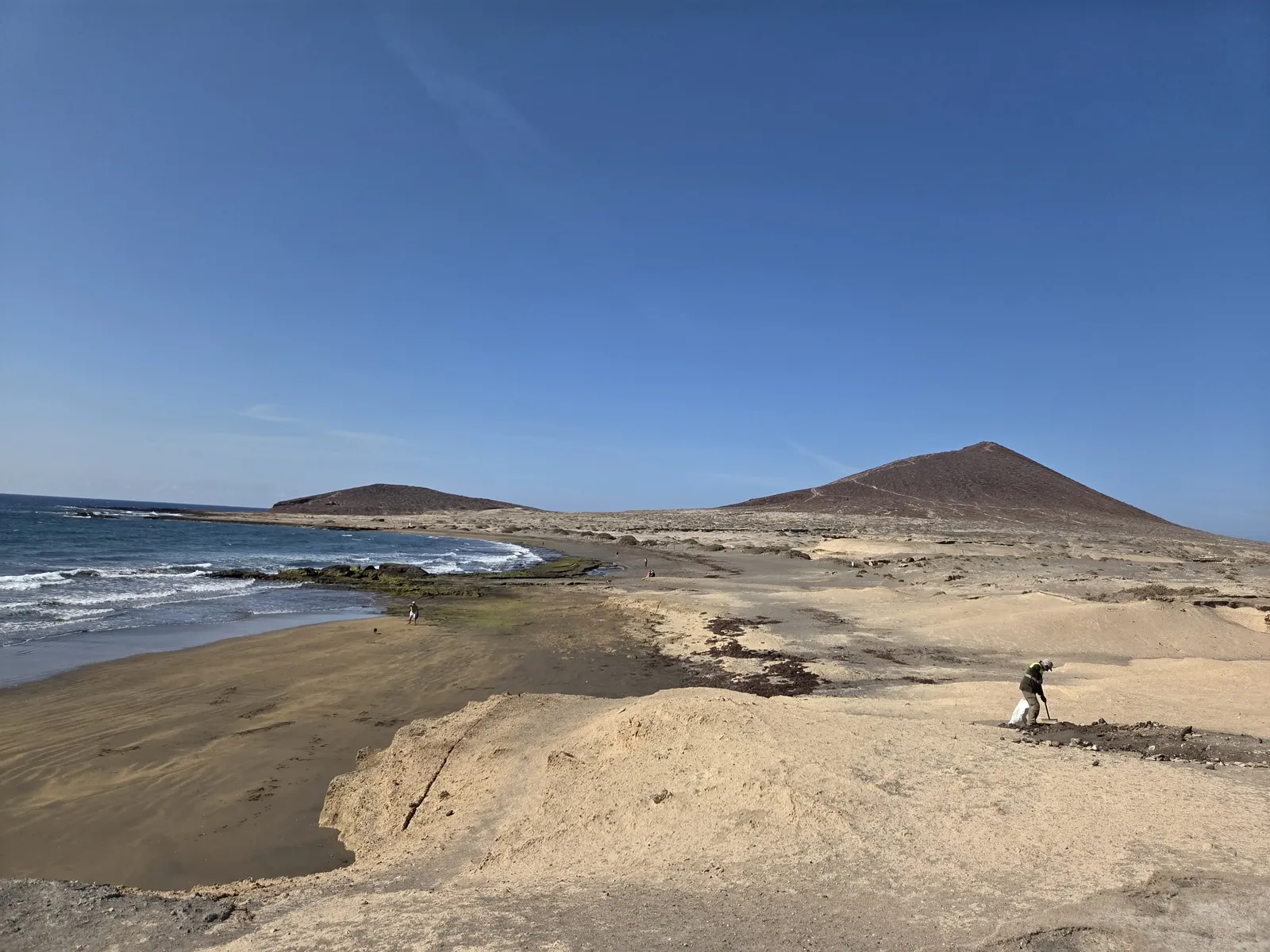 Cono volcánico de Montaña Roja visto desde la costa arenosa y rocosa de El Médano