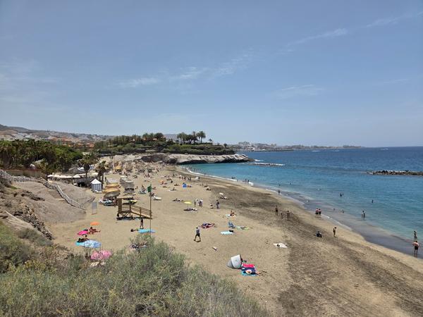 Playa del Duque Playa del Duque en el sur de Tenerife, con sombrillas, bañistas y un entorno turístico bien cuidado.