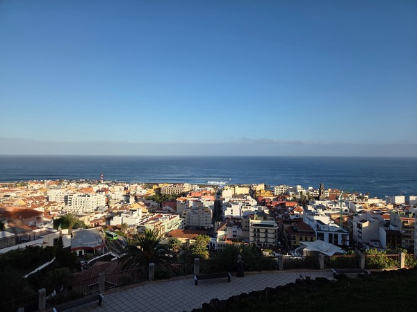 Vista elevada de Puerto de la Cruz con tejados, edificios y el océano Atlántico extendiéndose en el horizonte.